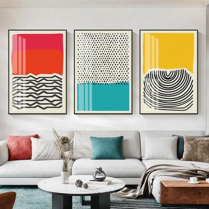 miaje salón con sofá claro y láminas de colores en la pared