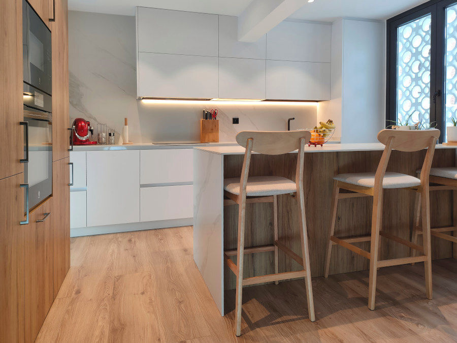 miaje cocina moderna con isla blanca y madera con encimera marmol claro con veta gris